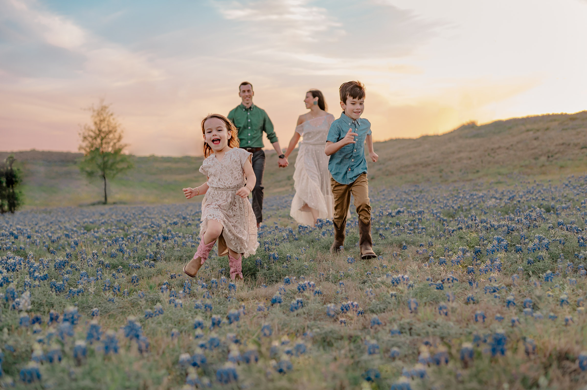 Family frolicking through a field of bluebonnets