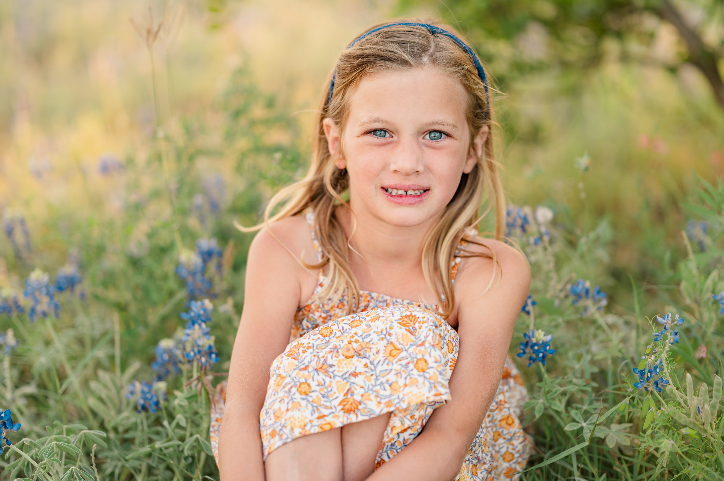 Beautiful golden portrait of a little girl sitting in San Antonio bluebonnets.