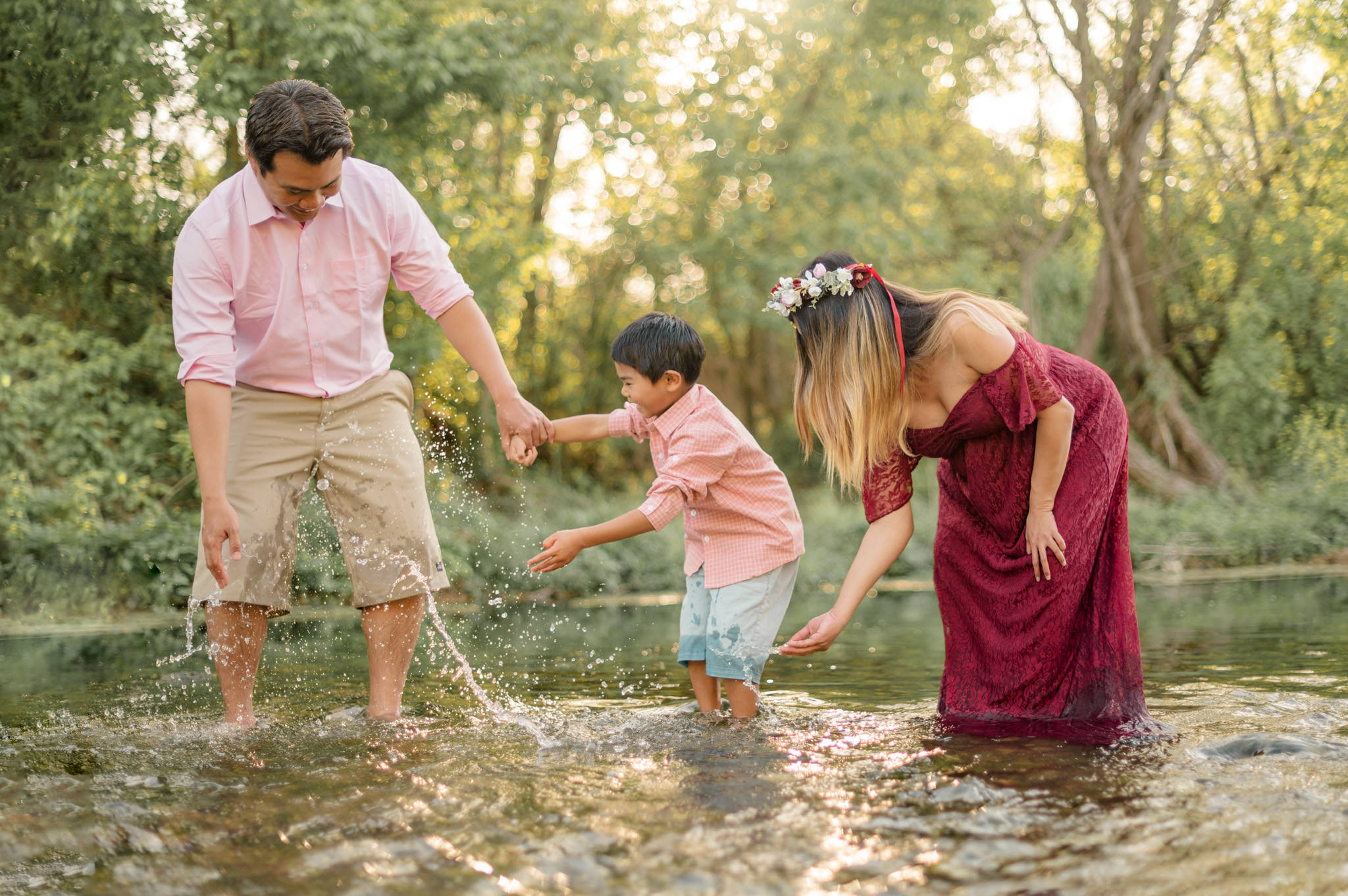 A young family of three playfully splashes each other from in the creek at Crescent Bend Nature Park. 