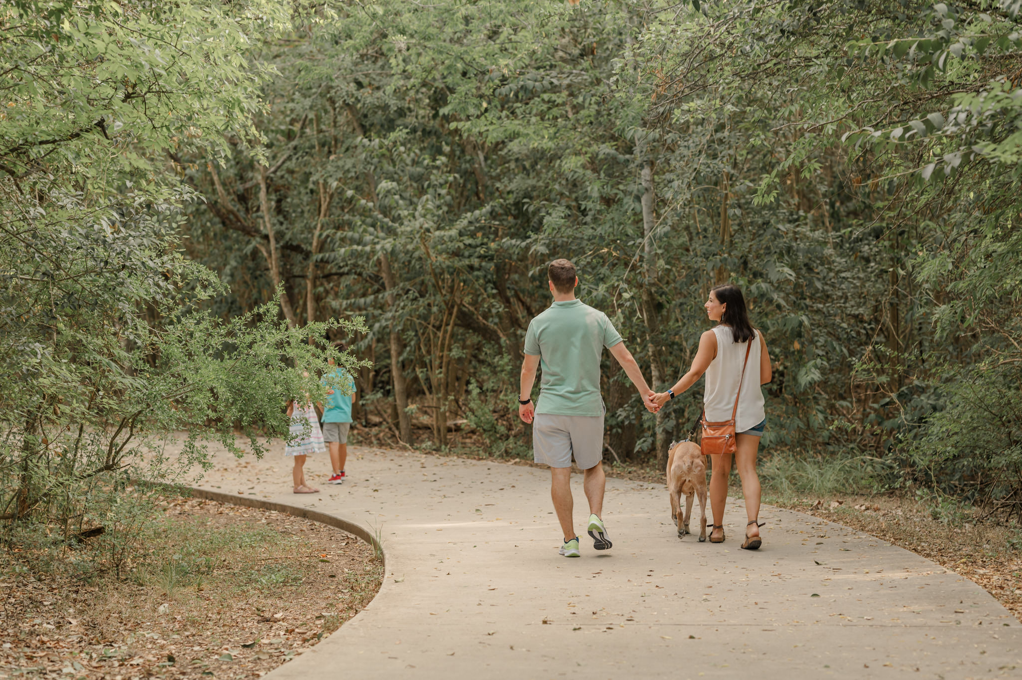 Family walks down a path away from the camera on their way to a San Antonio splash pad.