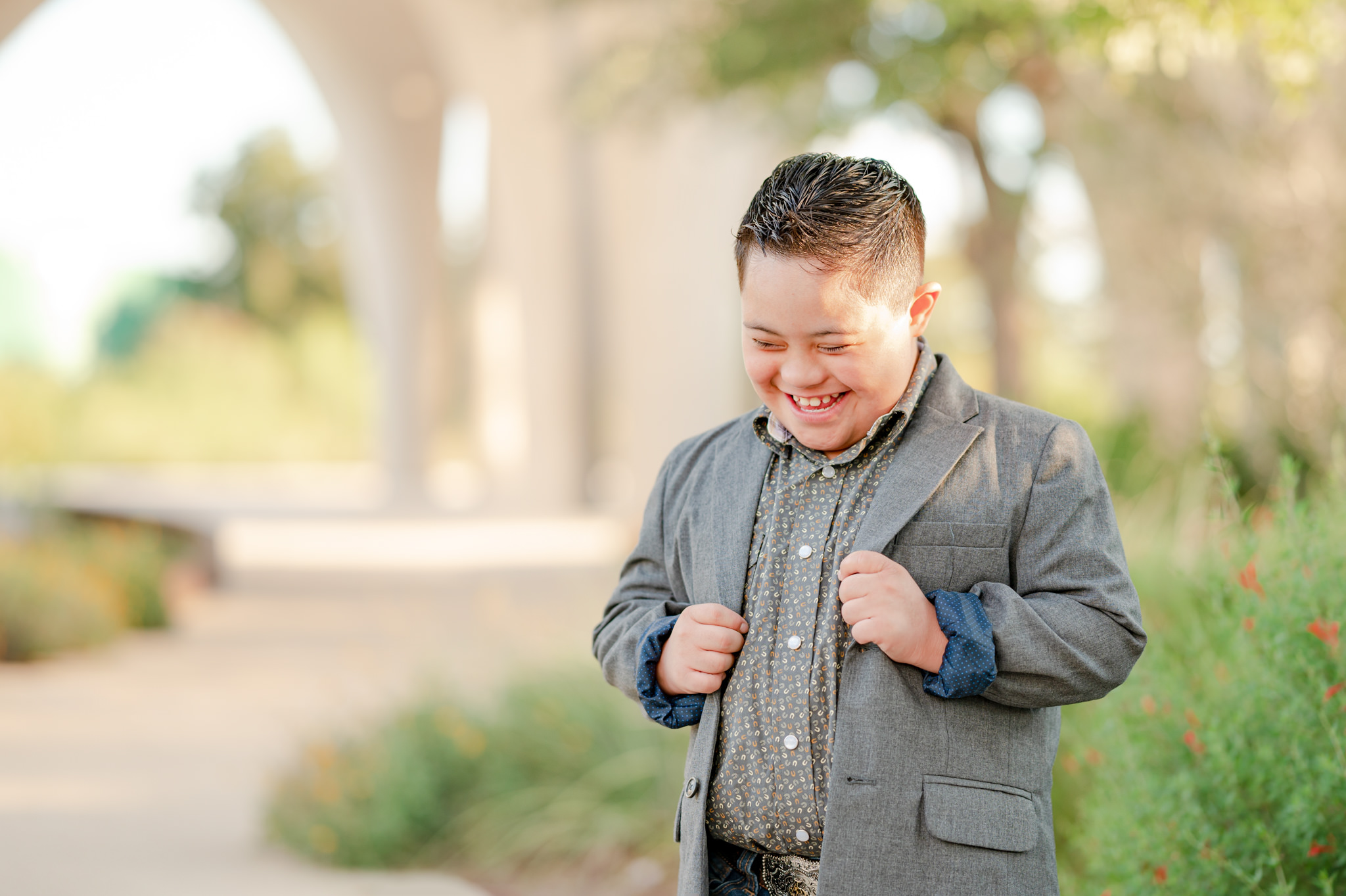 A young boy with Downy syndrome is dressed to the nines and laughing during photos with San Antonio special needs photographer Cassey Golden.