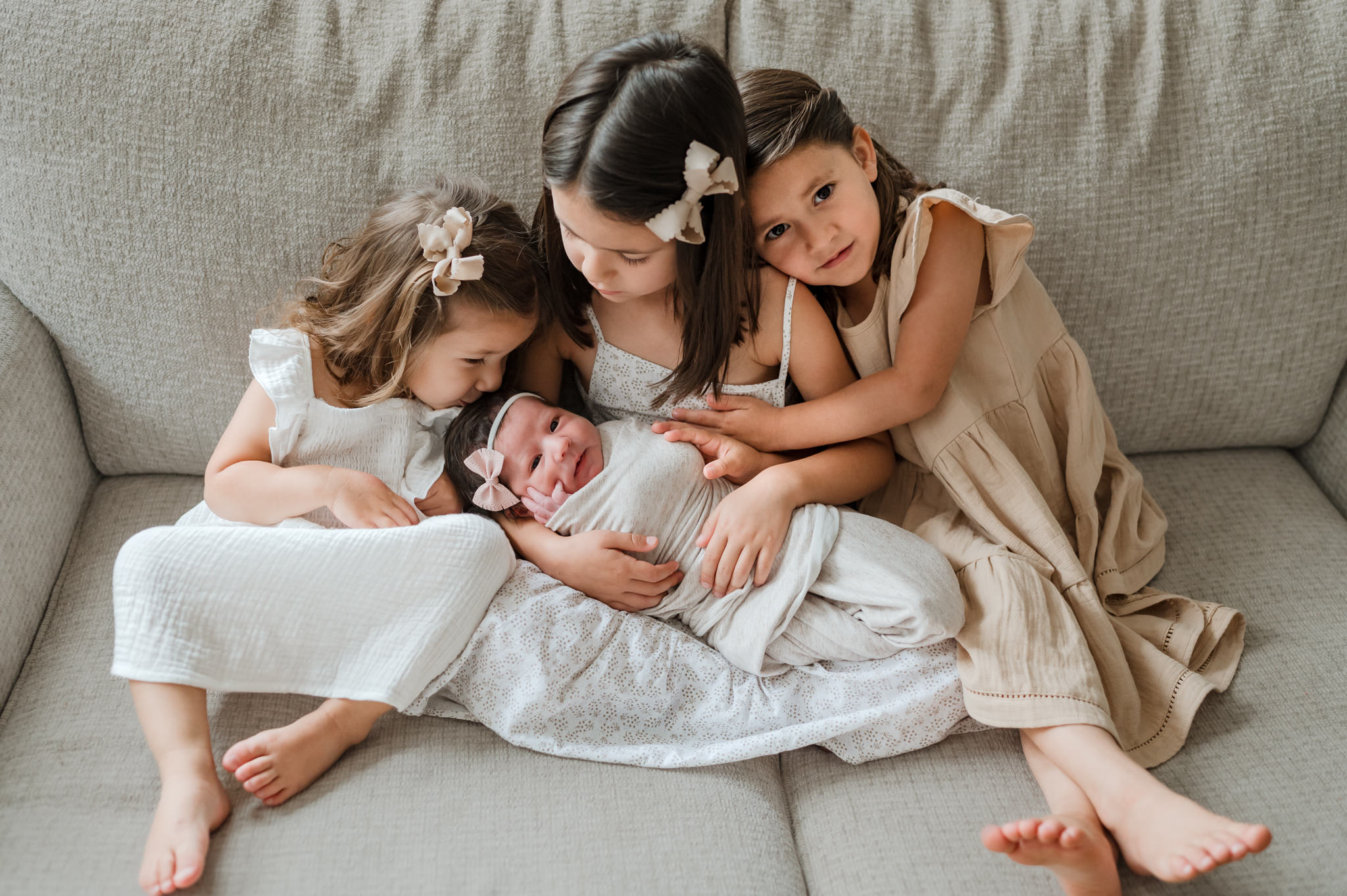 Three sisters sit on a couch in dresses while holding their newborn baby sister kid to kid san antonio
